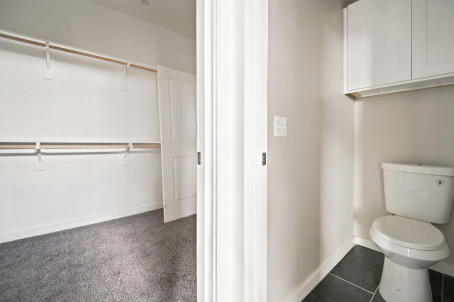 Functional layout connects a tiled water closet directly to a carpeted wardrobe area.