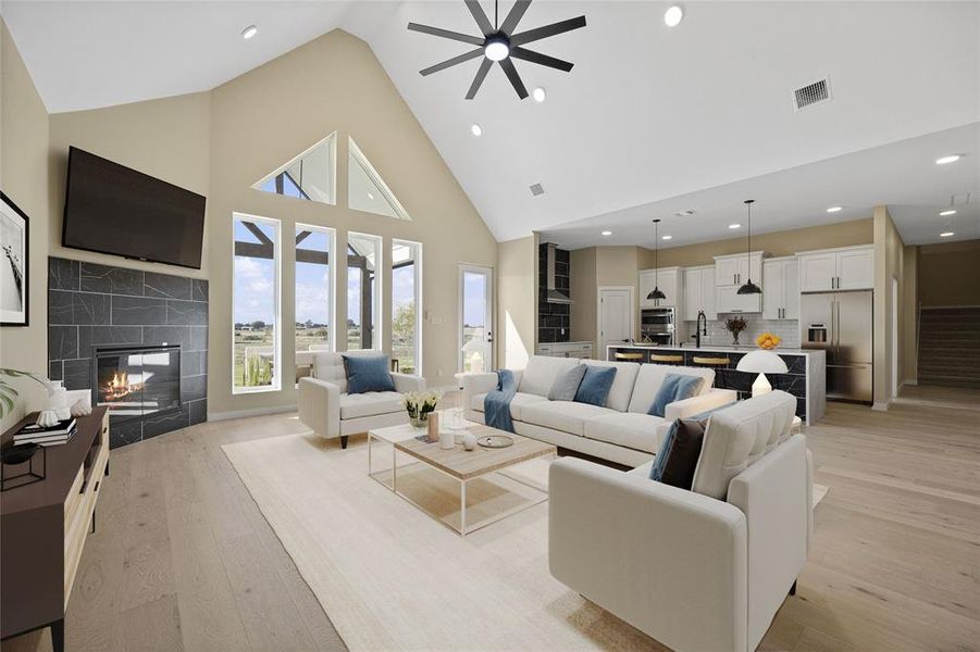 Living room featuring a tile fireplace, sink, light wood-type flooring, high vaulted ceiling, and ceiling fan