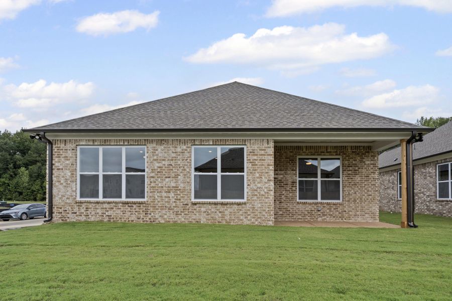 Back of house featuring a yard, brick siding, a shingled roof, and a patio