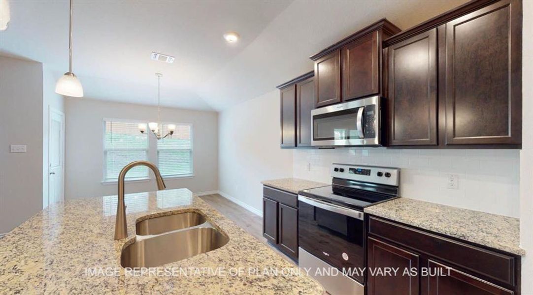Kitchen with appliances with stainless steel finishes, a sink, a chandelier, dark brown cabinets, and backsplash Kitchen with appliances with stainless steel finishes, a sink, a chandelier, dark brown cabinets, and backsplash