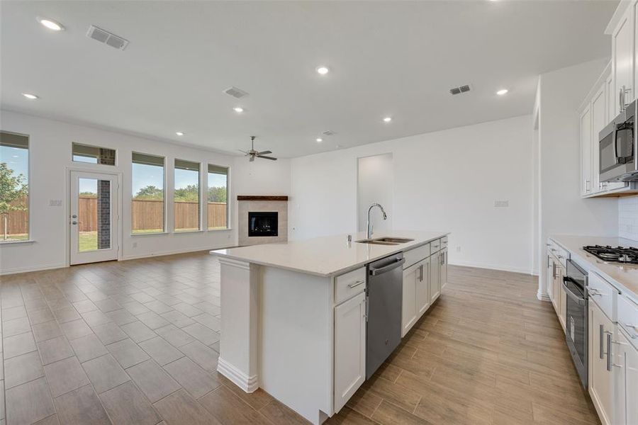 Kitchen featuring ceiling fan, white cabinets, sink, a center island with sink, and stainless steel appliances