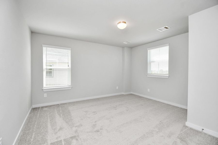 Secondary bedroom features plush carpeting, large windows that let in plenty of natural light, bright paint, and spacious closets. Sample photo of completed home with similar floor plan. Actual colors and selections may vary.