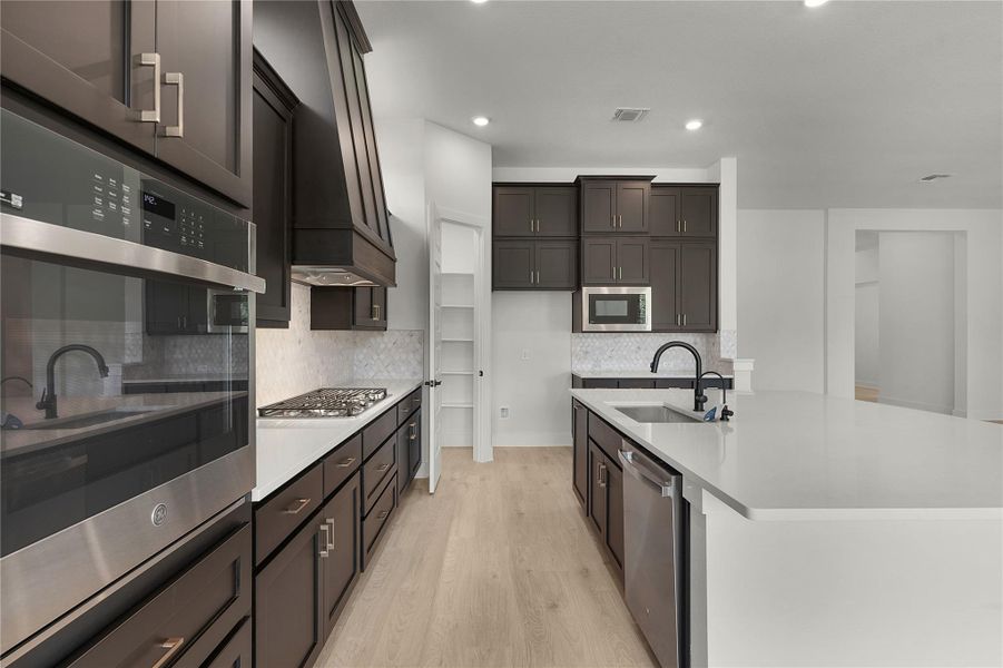 Kitchen featuring stainless steel appliances, light wood-style flooring, light countertops, tasteful backsplash, and recessed lighting Kitchen featuring stainless steel appliances, light wood-style flooring, light countertops, tasteful backsplash, and recessed lighting