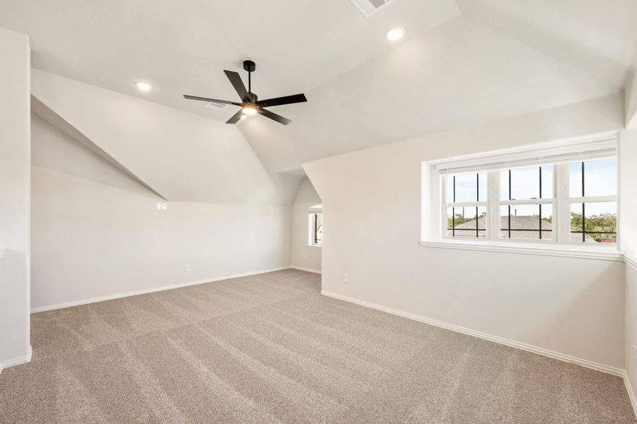 Empty bedroom with vaulted ceiling, ceiling fan, carpet flooring, and large windows