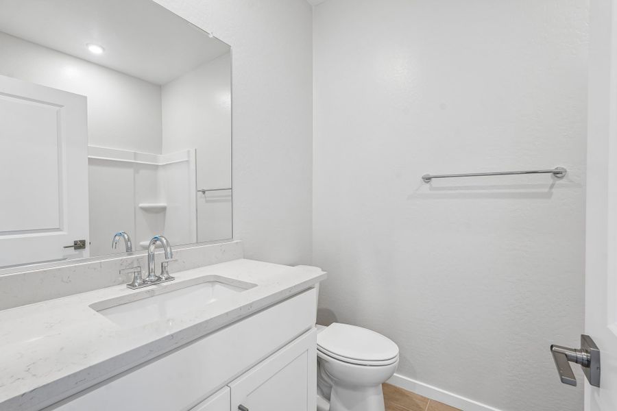 A bathroom with a sink toilet and mirror.