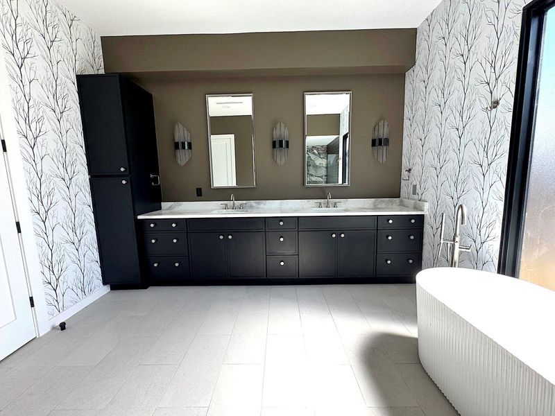 Bathroom with a sink, a freestanding bath, double vanity, and wallpapered walls