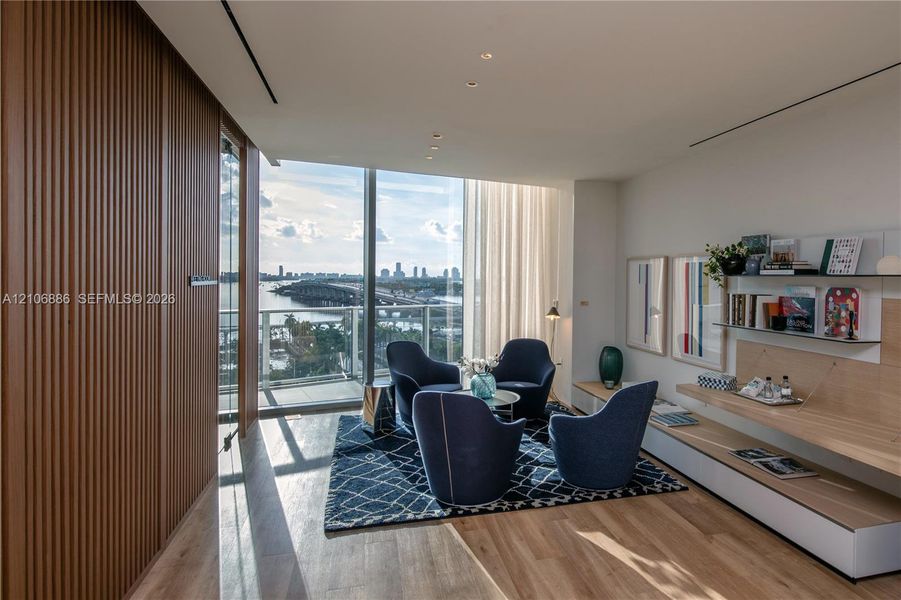 Floor-to-ceiling windows, integrated wood-slat wall paneling, built-in wall shelving with light wood finish, recessed ceiling lighting, and wood-finish flooring