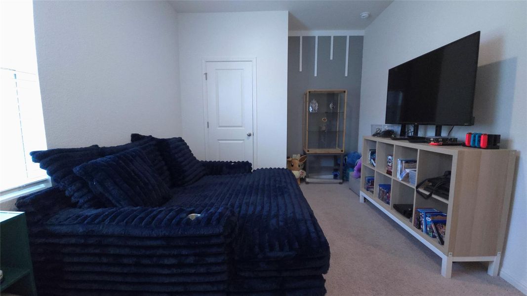 Spacious room featuring light-colored walls and carpeted flooring