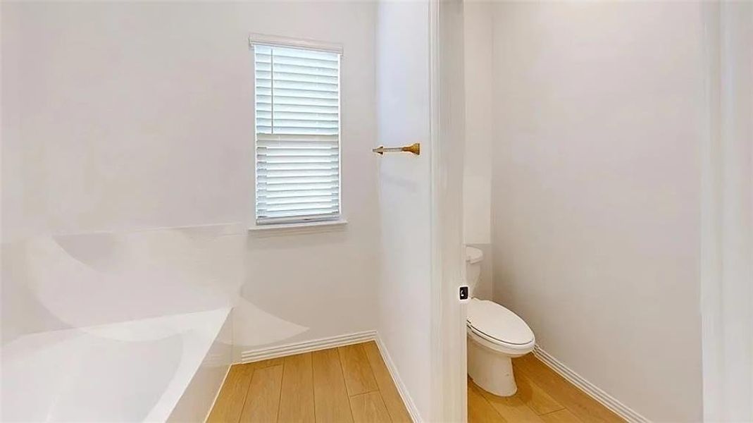 Full bath with wood finished floors and a bathtub