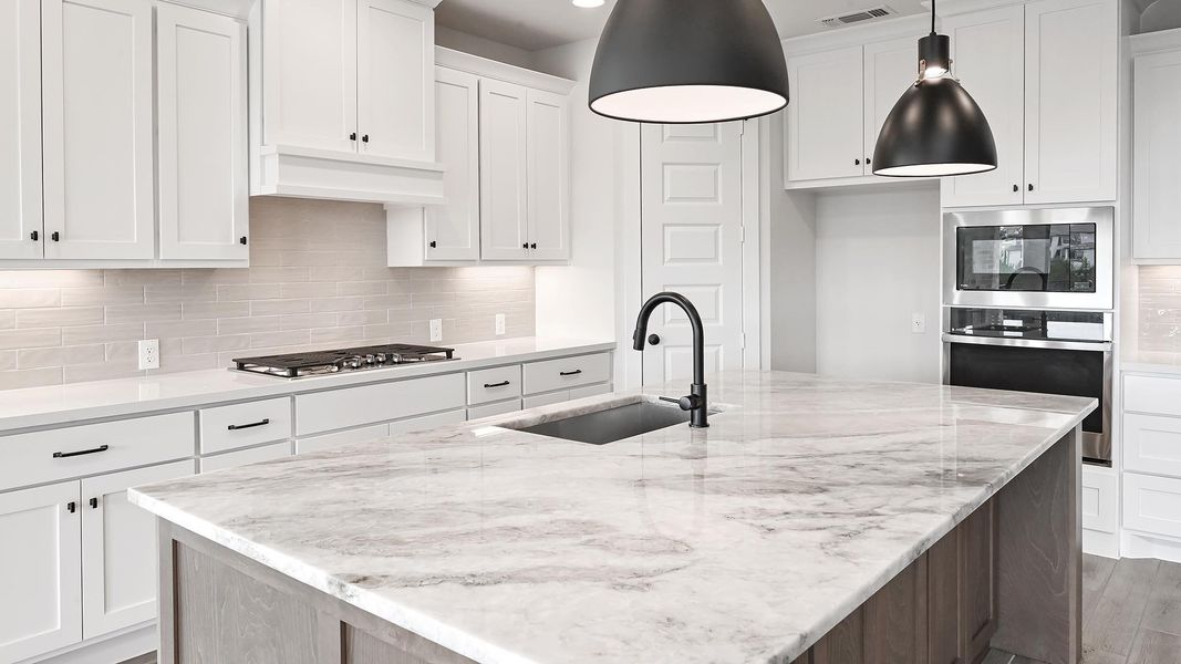 Kitchen with appliances with stainless steel finishes, white cabinets, a kitchen island with sink, light stone countertops, and decorative backsplash Kitchen with appliances with stainless steel finishes, white cabinets, a kitchen island with sink, light stone countertops, and decorative backsplash