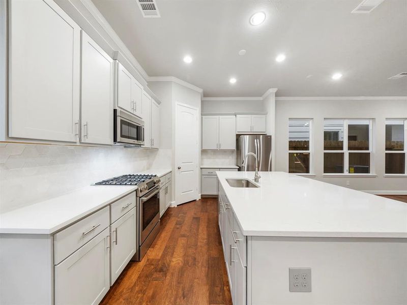 Step into a large and open kitchen, highlighted by the custom cabinets, stunning quartz countertops, and stainless-steel appliances! (Sample photo of a completed Sterling Floor Plan. Image may show alternative features/and or upgrades.)