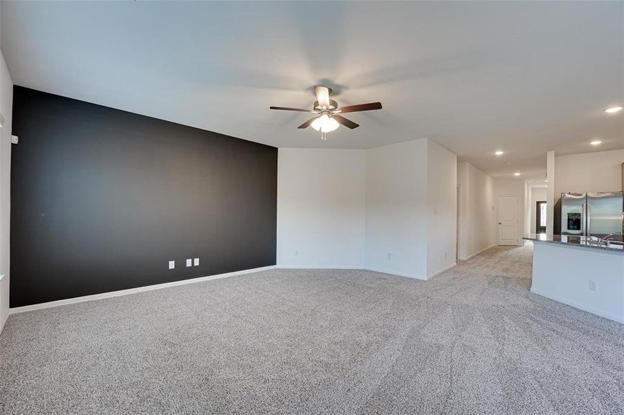 Unfurnished living room with ceiling fan and light colored carpet