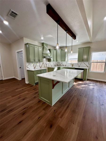Kitchen featuring a spacious island with a light-toned countertop, wood-finish flooring, and sage green cabinetry