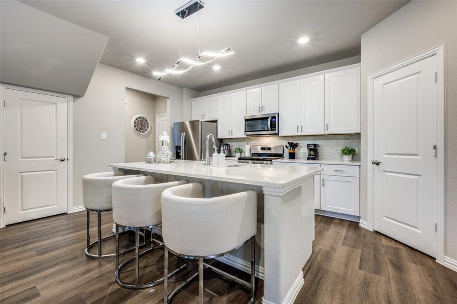 Kitchen with tasteful backsplash, white cabinets, hanging light fixtures, dark wood-style floors, and recessed lighting Kitchen with tasteful backsplash, white cabinets, hanging light fixtures, dark wood-style floors, and recessed lighting