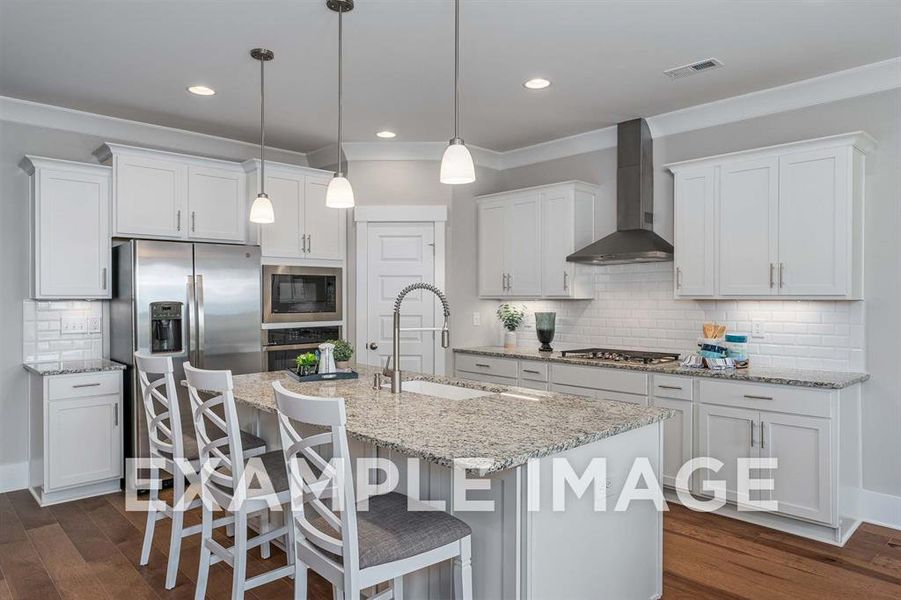 Kitchen with white cabinets, stainless steel appliances, a kitchen island with sink, and wall chimney range hood