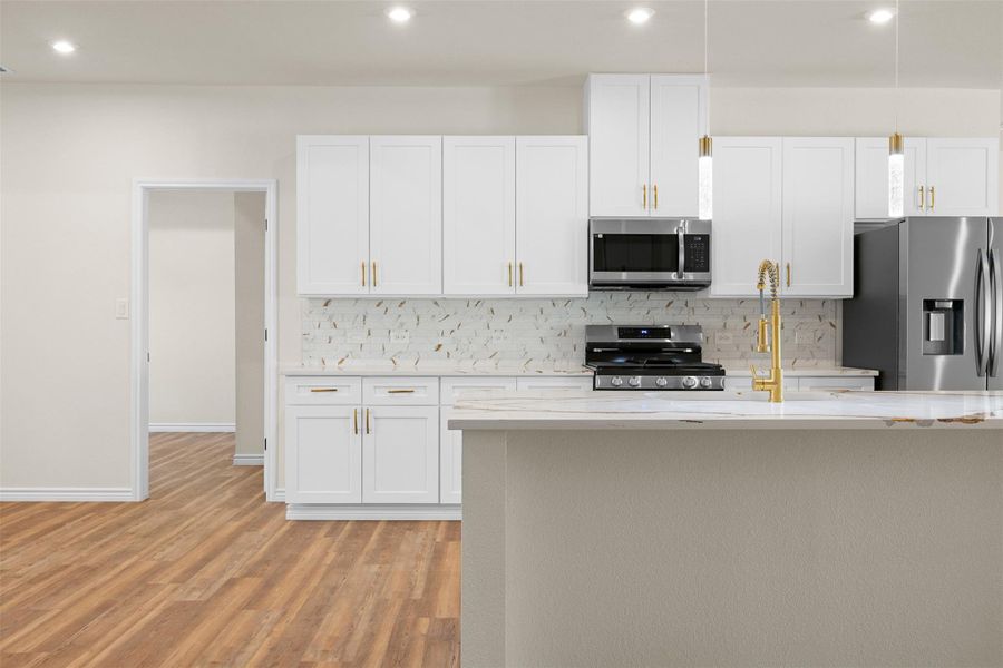Kitchen featuring stainless steel appliances, white cabinetry, light stone counters, backsplash, and light wood-style flooring Kitchen featuring stainless steel appliances, white cabinetry, light stone counters, backsplash, and light wood-style flooring