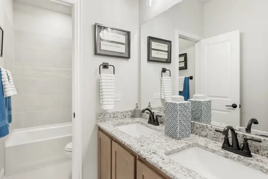 Bathroom with double sink vanity, granite countertops, and tiled shower-tub combo