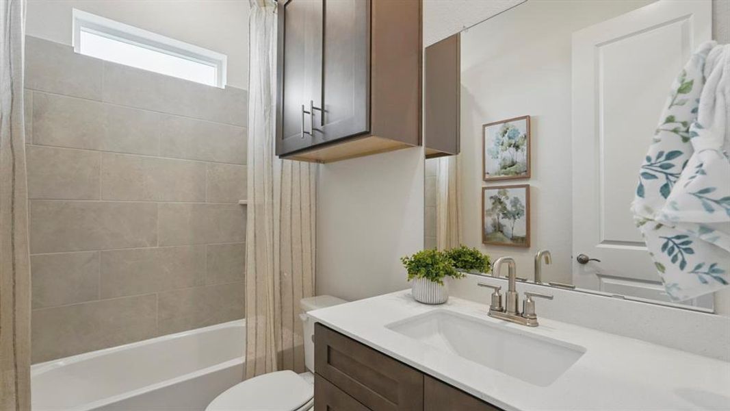 Bathroom featuring a built-in tub with large format tile surround, transom window, wood-finish vanity with an integrated sink, polished chrome faucet, and a large wall mirror