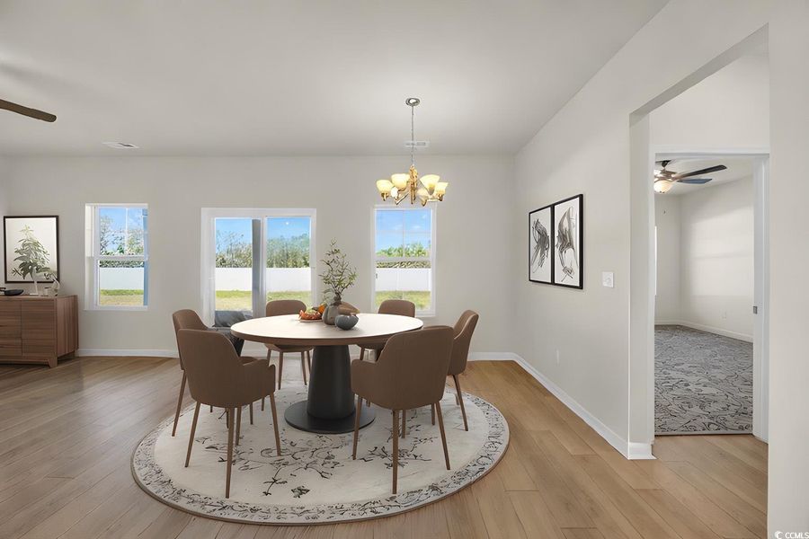 Dining room featuring light wood-type flooring, ceiling fan with notable chandelier, and baseboards