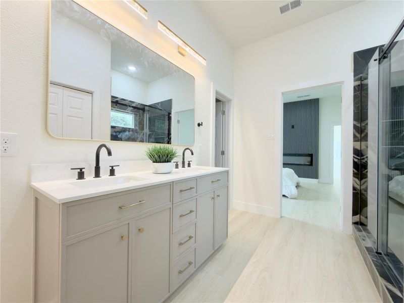 Bathroom featuring ensuite bathroom, double vanity, a shower stall, and light wood finished floors