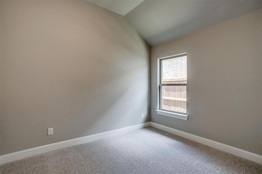 Spare room featuring carpet flooring and vaulted ceiling