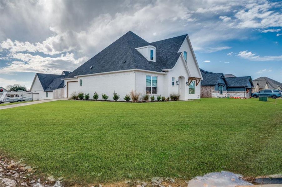 View of side of home featuring a garage and a lawn