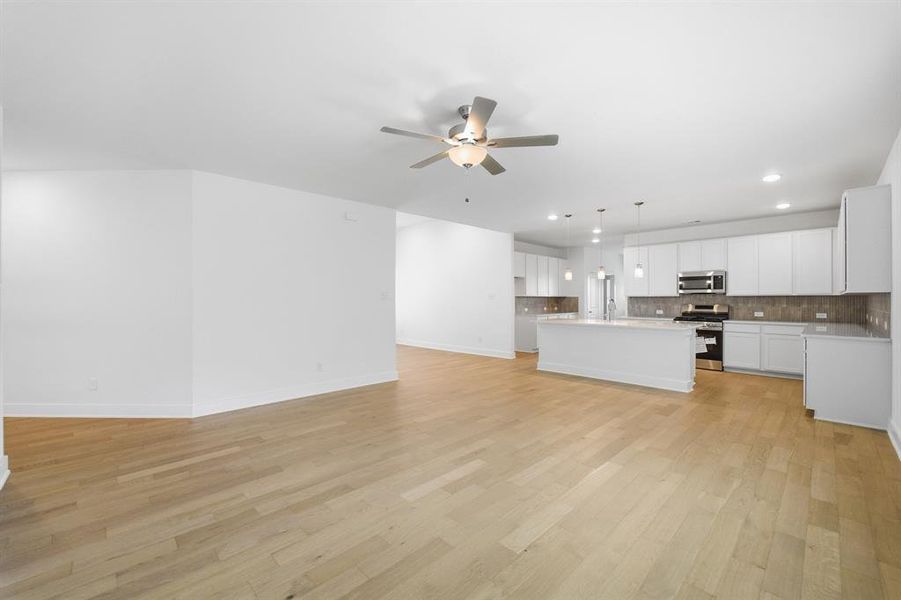 Open-concept living area with light wood-finish flooring, recessed lighting, and a modern ceiling fan
