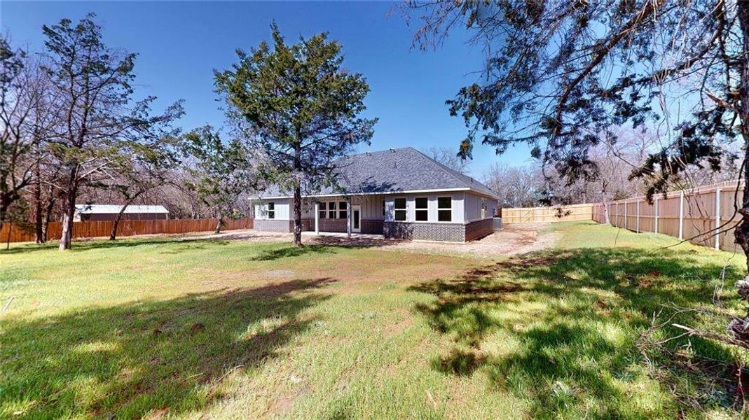 Rear view of house featuring brick siding, a lawn, and a fenced backyard