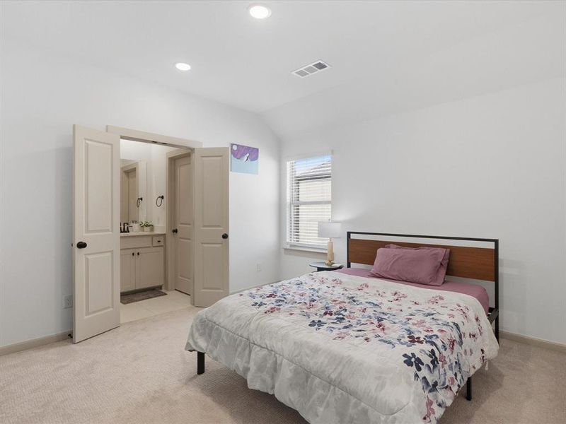 Bright bedroom featuring neutral carpeting, recessed lighting, and a window with blinds