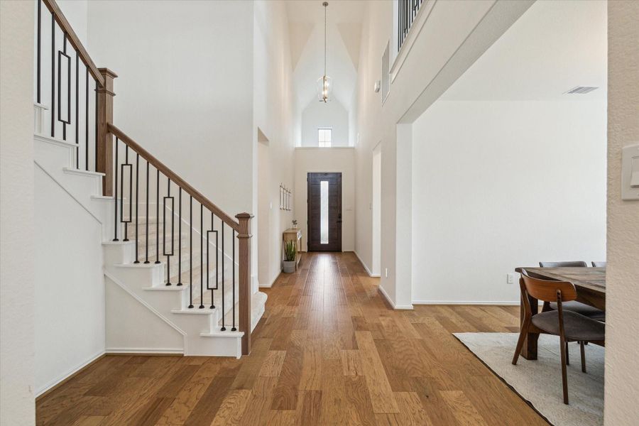 Front entry perspective showcasing the natural transition to the dining room and the staircase leading to the upper level.