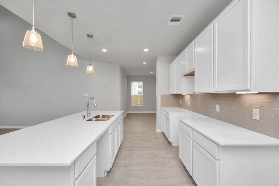Discover another perspective of this stunning kitchen, generously appointed with an abundance of counter space. Sample photo of completed home with similar plan. As built color and selections may vary.