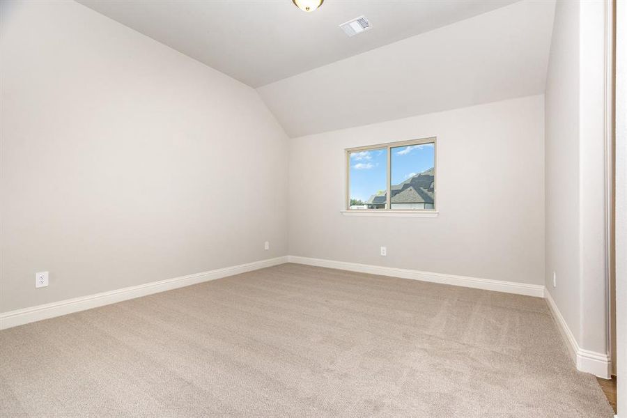 Empty room featuring light carpet and lofted ceiling
