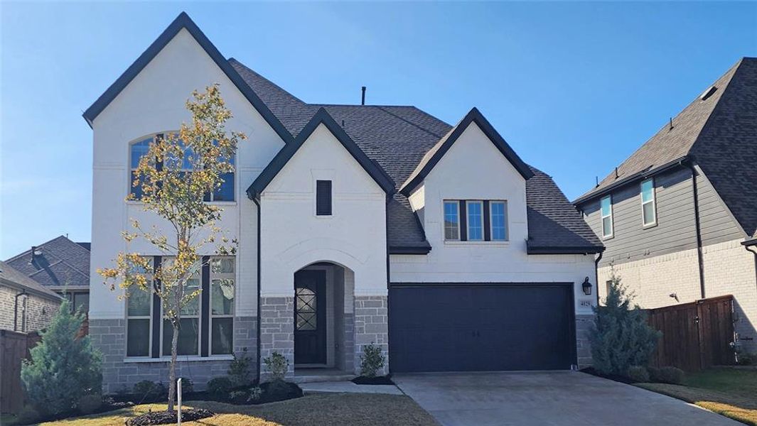 View of front of home with stucco siding, driveway, a shingled roof, and a garage