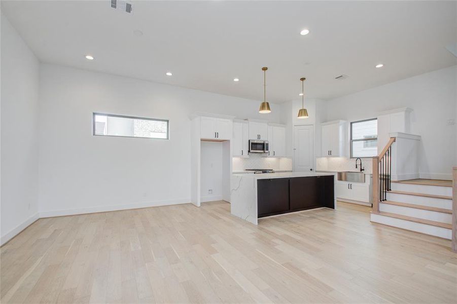 Bright and white kitchen with calacatta quartz waterfall countertop on the island. Photos of similar completed home by same builder. Selections may differ,