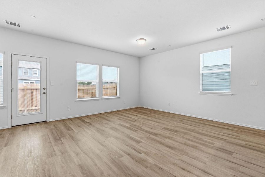 Spacious room featuring wood-finish flooring, white walls, and multiple windows Spacious room featuring wood-finish flooring, white walls, and multiple windows
