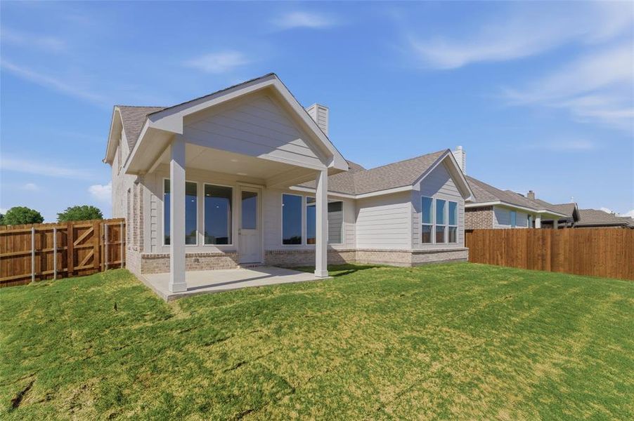 Rear view of house with a fenced backyard, a patio area, a chimney, brick siding, and roof with shingles
