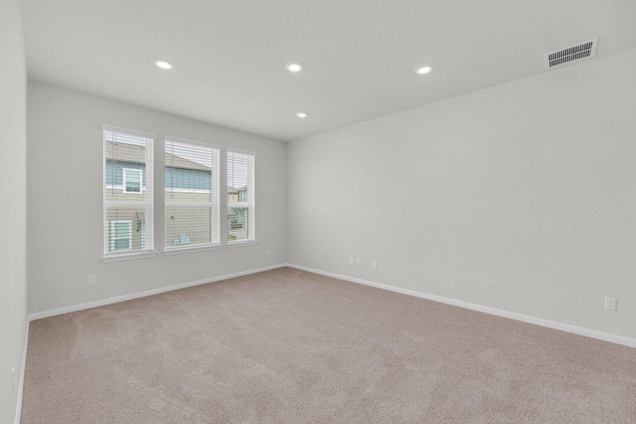 Empty room with light carpet and recessed lighting