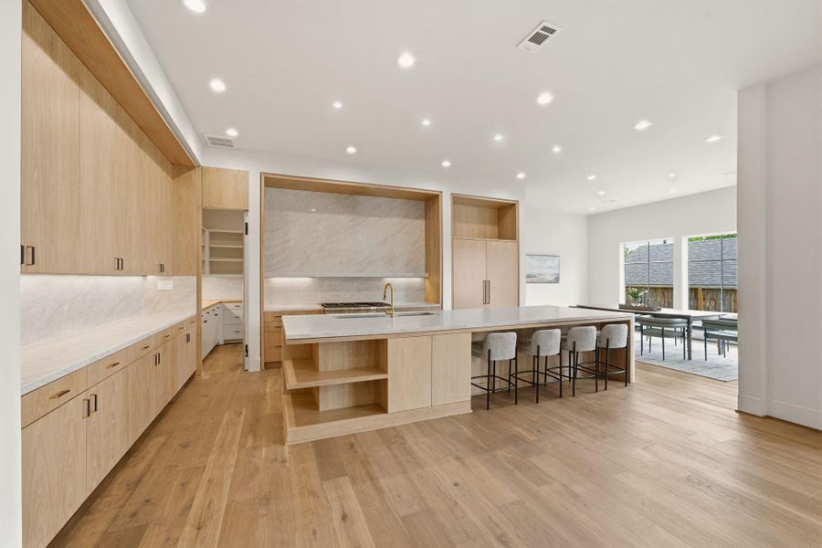 Clean lines and warm white oak accents define this thoughtfully designed chef’s kitchen. (Pendants over island to be installed).