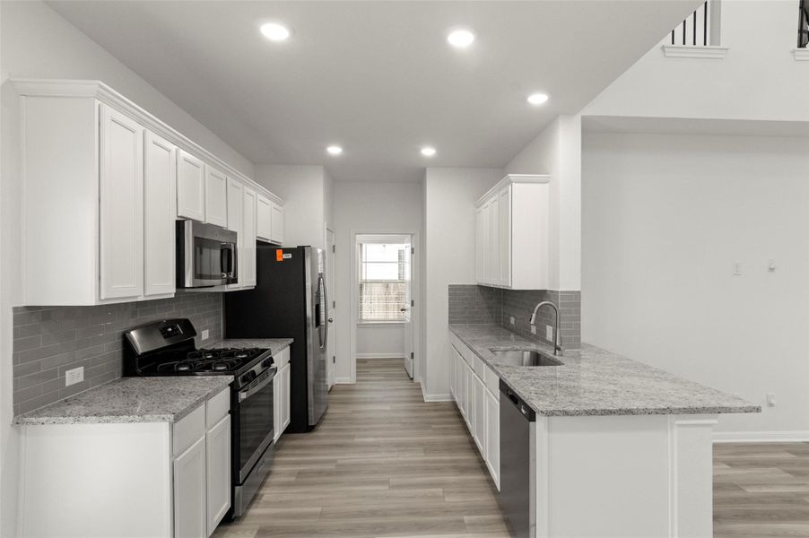 Kitchen with appliances with stainless steel finishes, decorative backsplash, recessed lighting, white cabinetry, and light wood-style floors Kitchen with appliances with stainless steel finishes, decorative backsplash, recessed lighting, white cabinetry, and light wood-style floors