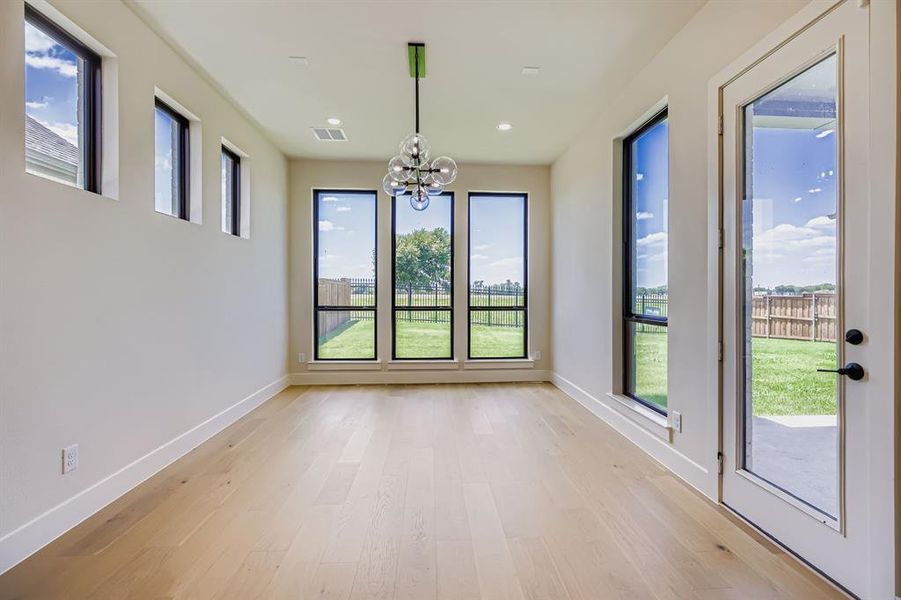 Unfurnished dining area with healthy amount of natural light, light wood-type flooring, a chandelier, and recessed lighting