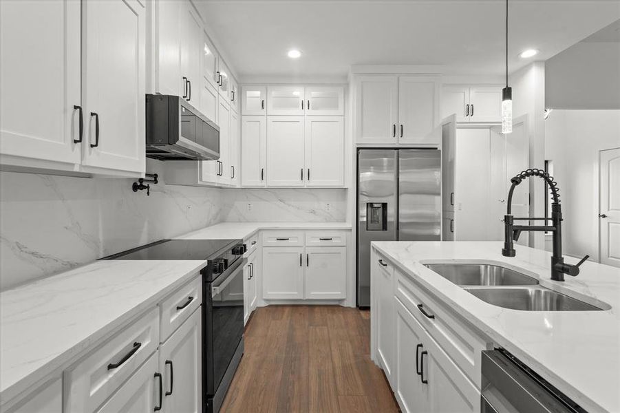 Kitchen with dark hardwood / wood-style flooring, white cabinets, pendant lighting, and appliances with stainless steel finishes