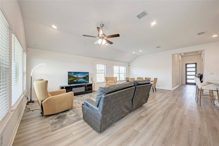 An airy living area offers light wood flooring, ample natural light, and a functional ceiling fan.