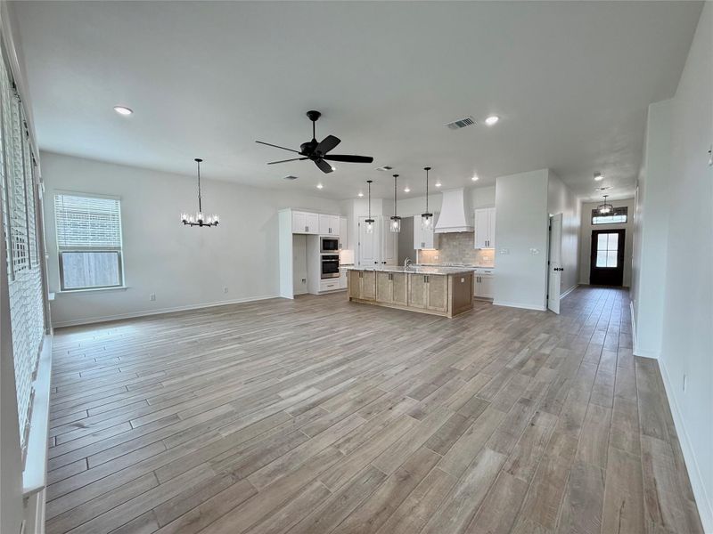 Spacious open-concept living area featuring wood-finish flooring, recessed lighting, and a modern ceiling fan