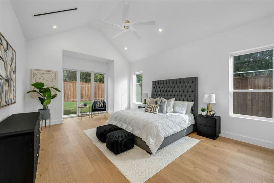 Bedroom with high vaulted ceiling, light wood finished floors, a ceiling fan, recessed lighting, and access to exterior
