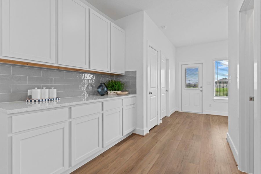 Extended counter space and upper/lower cabinetry provide exceptional storage and prep areas, with a hallway leading to the patio and additional living zones. **Image Representative of Plan Only and May Vary as Built**.