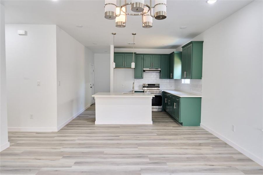 Open-concept living area featuring light wood-finish flooring and a contemporary chandelier