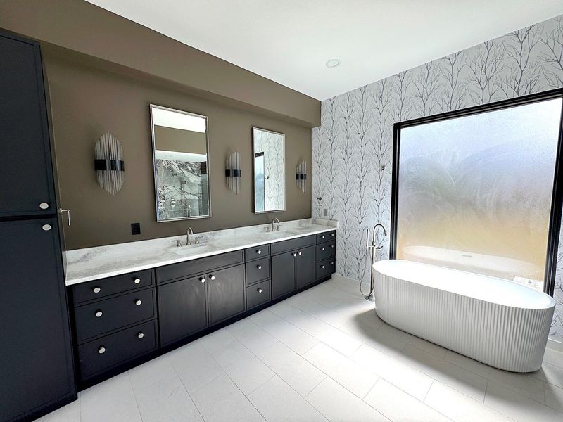 Bathroom featuring wallpapered walls, double vanity, a soaking tub, and a sink