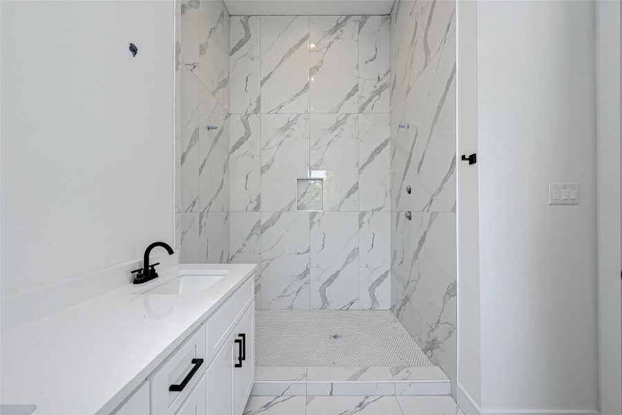 The spa-inspired walk-in shower is wrapped in elegant porcelain tile with dramatic veining, offering a luxurious retreat in the primary en-suite bathroom.