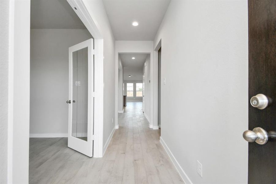 The grand entrance beckons with its soaring ceilings, adorned with elegant wood-look tile flooring featuring sleek oversized baseboards. Photo shown is example of completed home with similar plan. Actual colors and selections may vary.