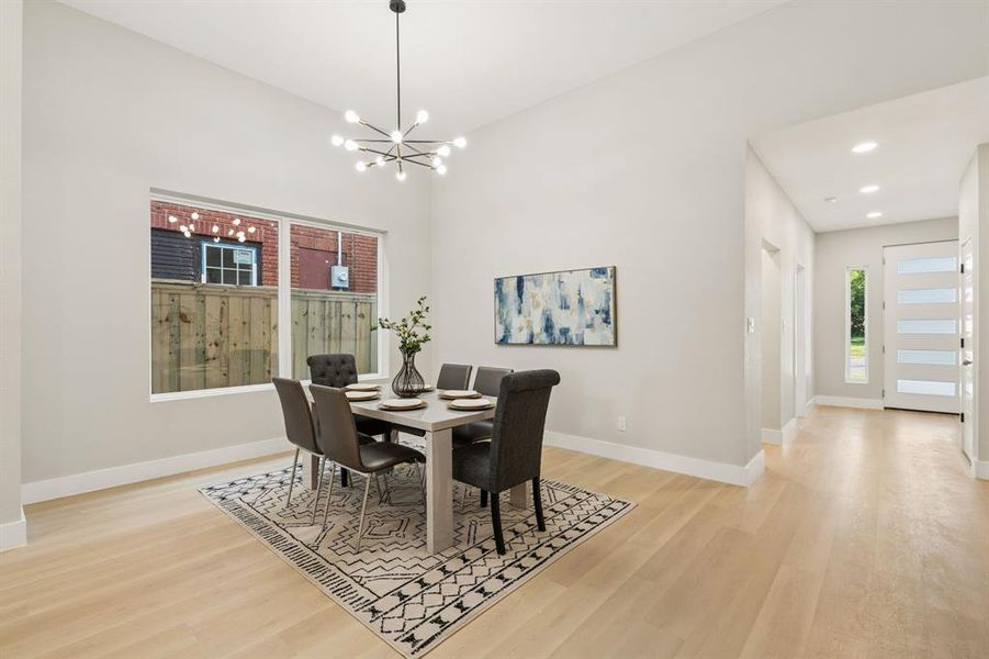 Spacious dining area featuring wood-finish flooring, a contemporary chandelier, and a large window Spacious dining area featuring wood-finish flooring, a contemporary chandelier, and a large window
